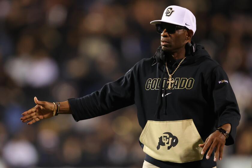 Colorado coach Deion Sanders extends his hand out to high-five his players during a football game against Colorado State.