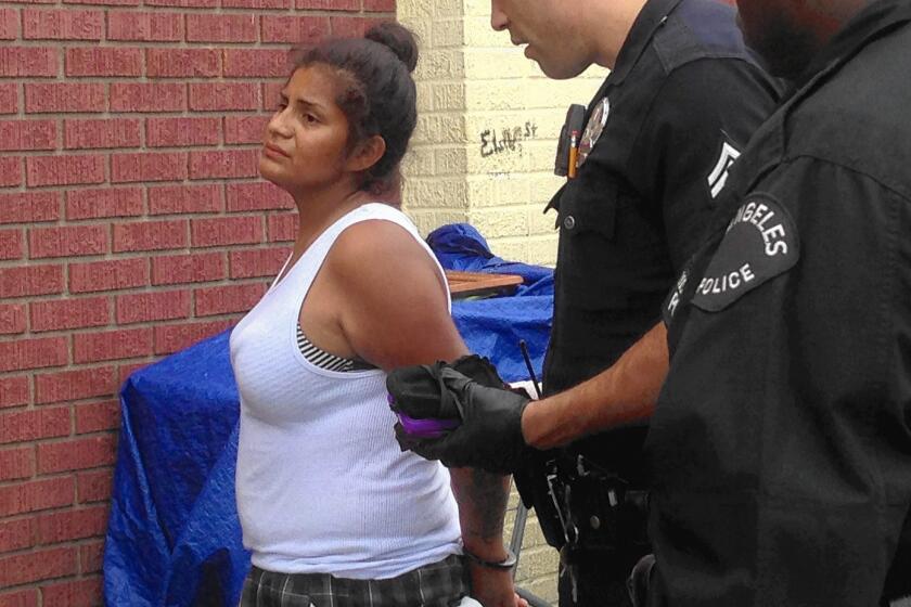 A woman is arrested in July during an LAPD sweep of skid row camps.
