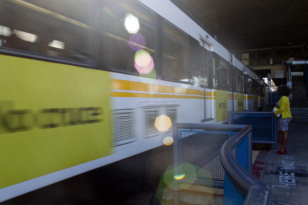 A pedestrian waits as a Blue Line train passes by at the Willowbrook-Rosa Parks Metro station in Los Angeles.