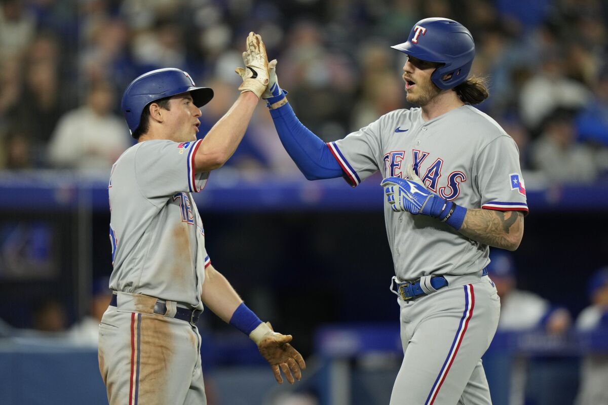Texas Rangers catcher Jonah Heim, right, is congratulated by teammate Brad Miller after Heim hit a two-run home run against the Toronto Blue Jays during the seventh inning of a baseball game Sunday, April 10, 2022 in Toronto. (Frank Gunn/The Canadian Press via AP)