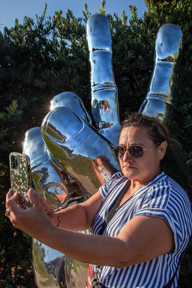 Raquel Morales, 60, of Los Angeles, takes a selfie in front of 800-pound "Peace and Love" statue.