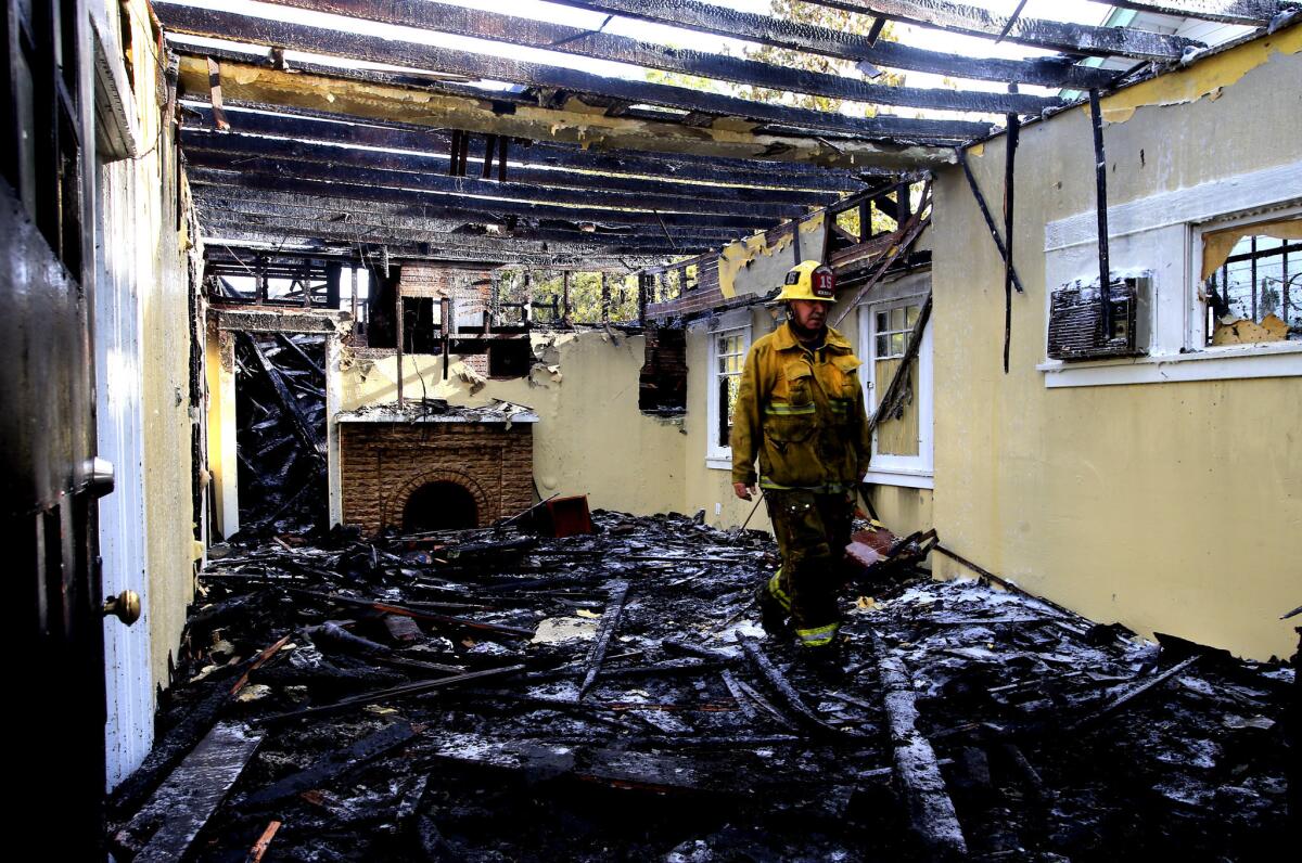 Los Angeles fireman Eric Dillon walks through the rubble of a home destroyed by fire in the 1500 block of West 37th Street in Los Angeles on Wednesday morning. One firefighter was hospitalized with injuries he suffered while fighting the blaze. The cause of the fire is under investigation.