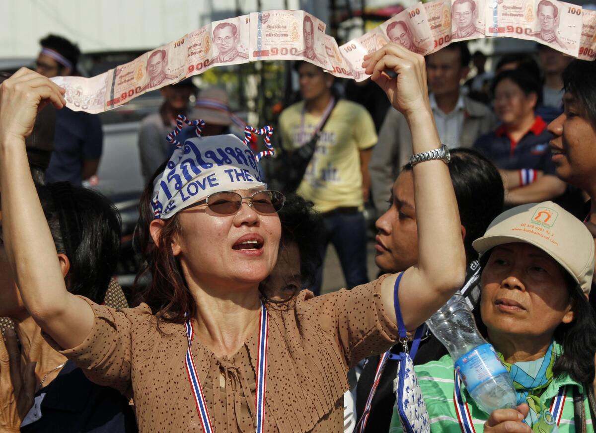 An anti-government supporter displays her donations for the cause during a street rally in central Bangkok, Thailand, on Tuesday. Thailand has declared a state of emergency in Bangkok and its surrounding areas because of protests.