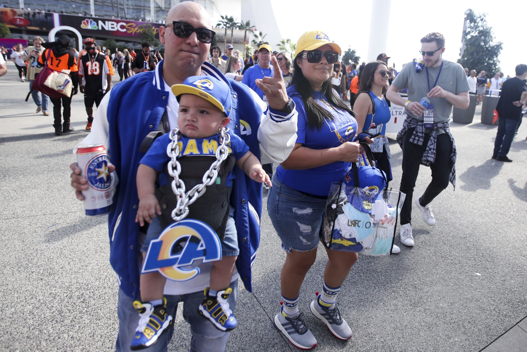 A Rams fan walks with his baby strapped to him outside of SoFi Stadium.