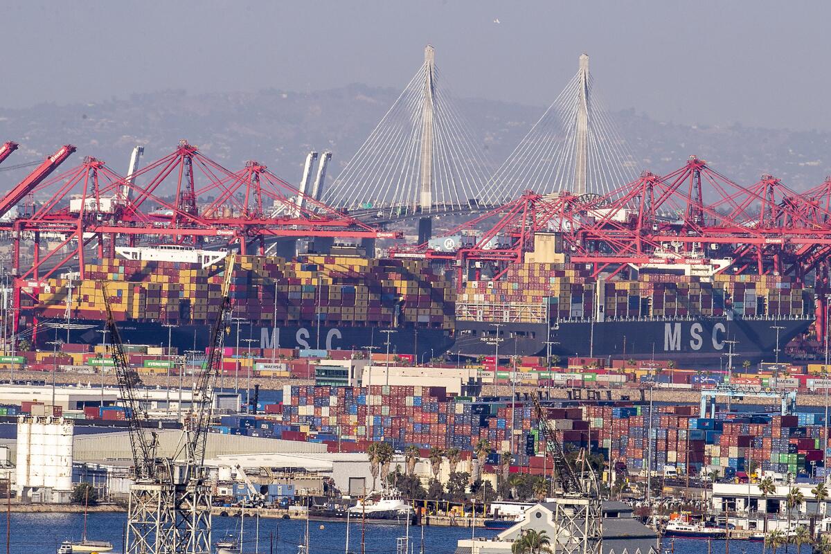 A view of stacked containers in the foreground and container ships in the background.