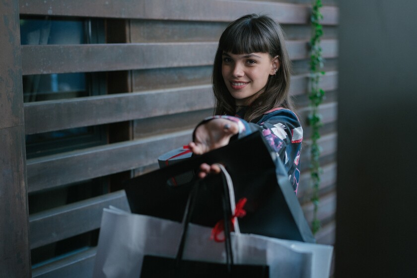 A smiling teenage girl holds out gift bags