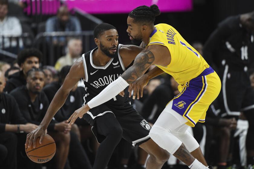 Brooklyn Nets forward Mikal Bridges, left, defends the ball from Los Angeles Lakers guard D'Angelo Russell, right, during the first half of a preseason NBA basketball game Monday, Oct. 9, 2023, in Las Vegas. (AP Photo/Sam Morris)