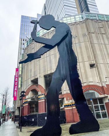 A large sculpture by Jonathan Borofsky, "Hammering Man," in front of a building