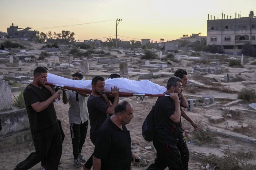 Palestinian mourners carry their loved one for burial at the cemetery in Deir al-Balah, Gaza Strip, Friday, Aug. 9, 2024. (AP Photo/Abdel Kareem Hana)