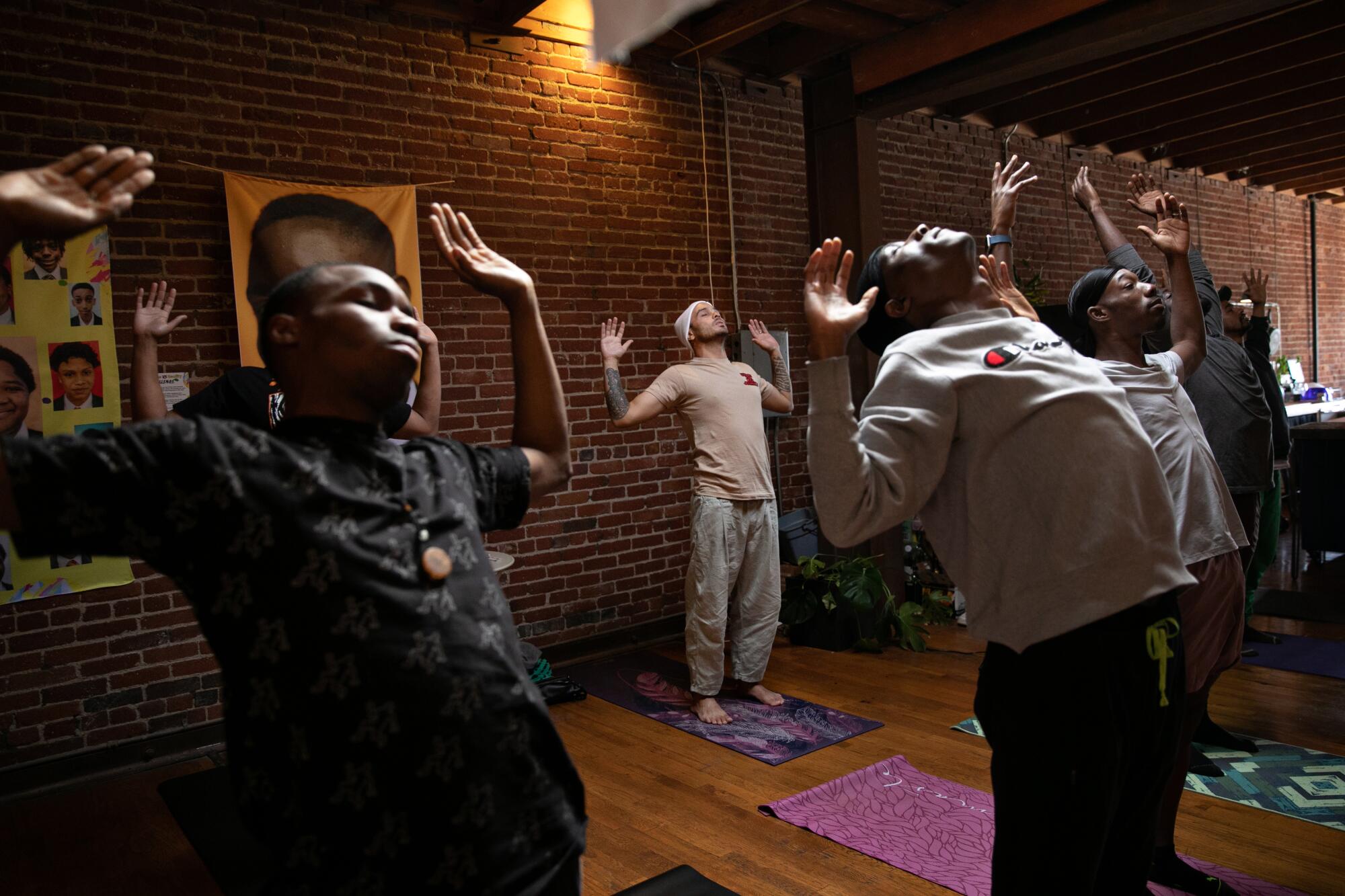 Bobby Brown, back row, stands with his arms open wide as he meditates with other Black men in a healing circle.