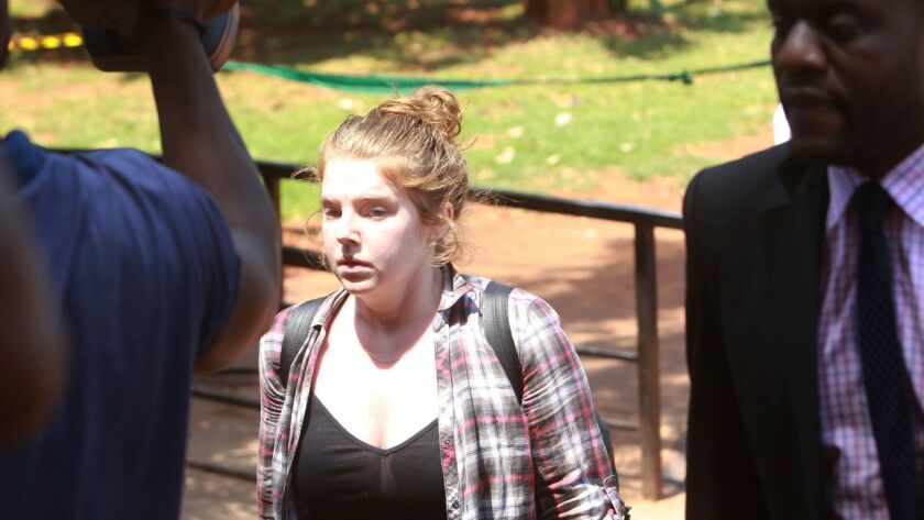 U.S. citizen Martha O' Donovan, escorted by a plainclothes police officer, appears at the Harare Magistrates Court on Saturday.