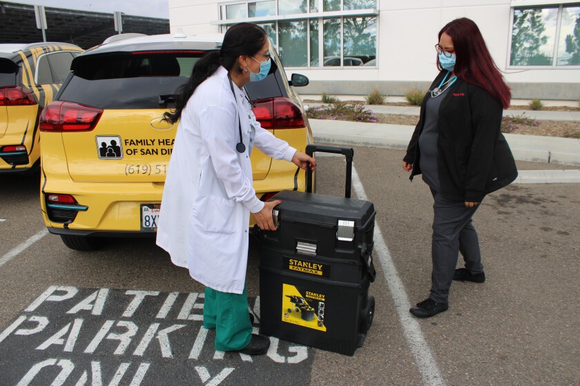 Maribel Marín, enfermera con Family Health Centers y Wanda Ramírez, frente a los vehículos del programa Tiger Teams.