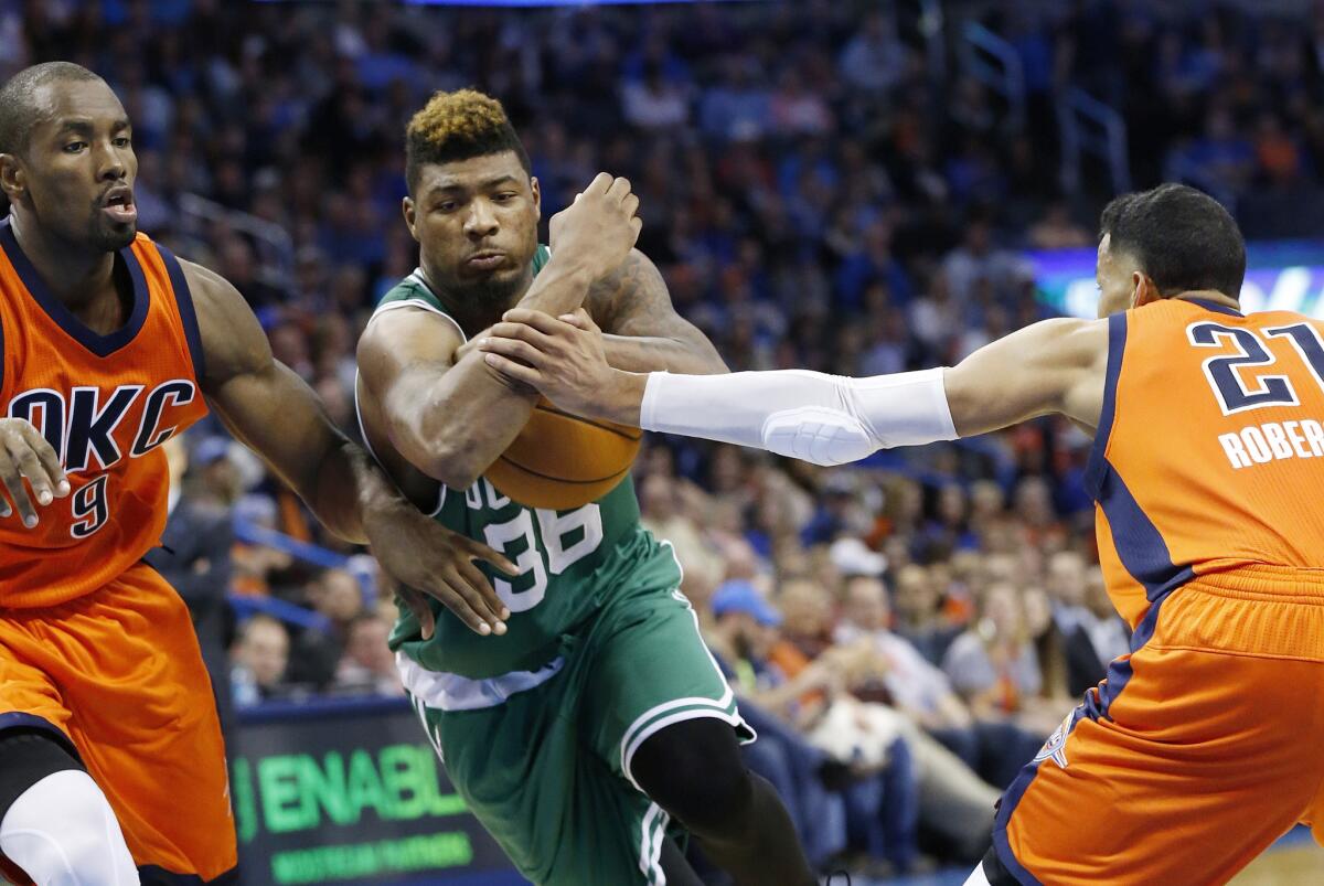 Celtics guard Marcus Smart drives between Oklahoma City Thunder forward Serge Ibaka (9) and guard Andre Roberson (21) during the third quarter. Boston won 100-85.
