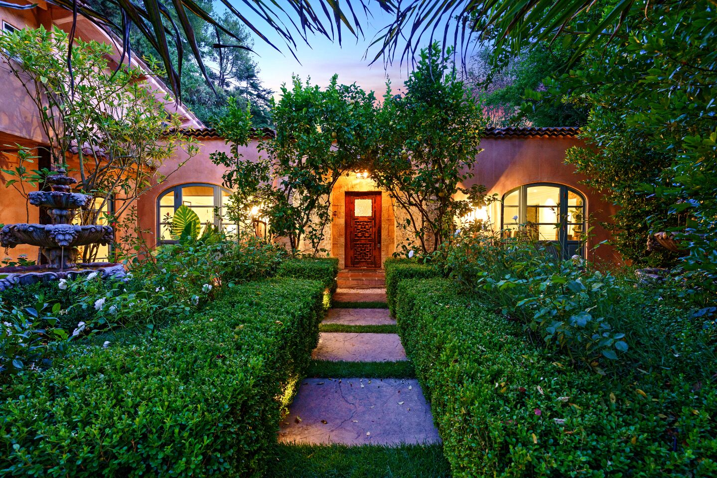 Hedges and large stone pavers lead up the the entrance of a Mediterranean-style home in the Hollywood Hills