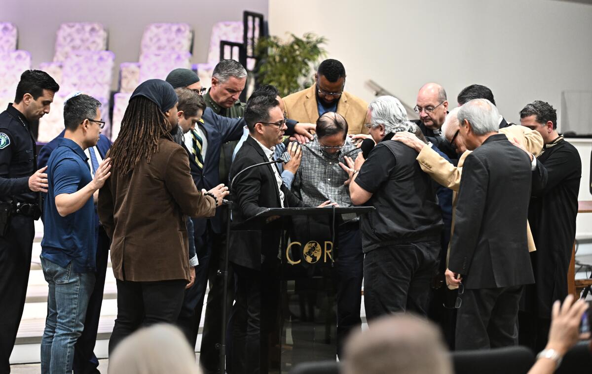 Officials pray around Billy Chang during a vigil at Christ Our Redeemer A.M.E. Church in Irvine Monday. 