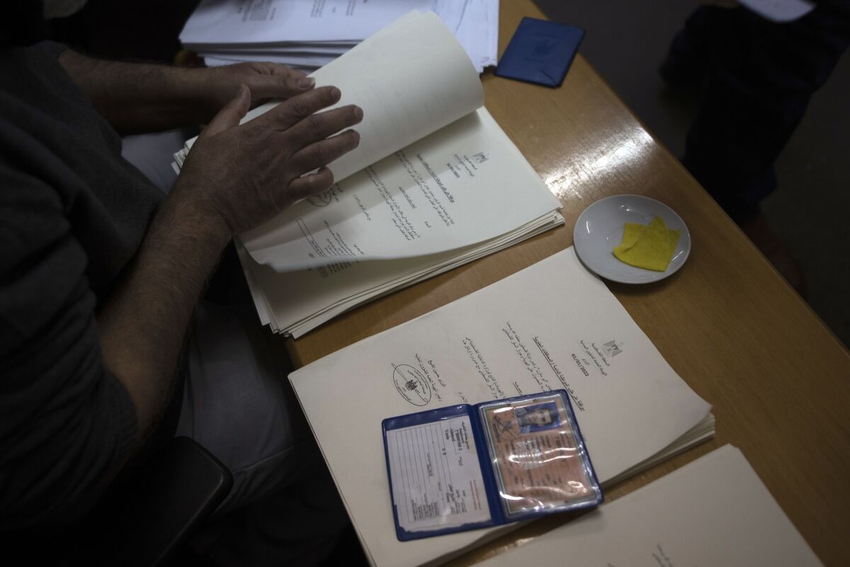 A Palestinian civil affairs employee looks for a name among the letters officially approved by Israel, in his office in Gaza City, Monday, Jan. 3, 2022. In recent months, Israel has approved residency for thousands of Palestinians in the occupied West Bank and Gaza, allowing them to get an official Palestinian ID number that grants them the possibility to travel abroad and clear up years of uncertain legal status. (AP Photo/ Khalil Hamra)