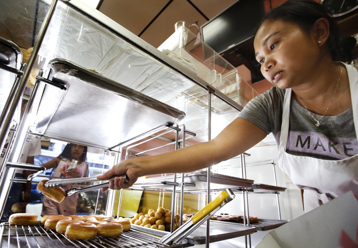 Srim Chhun, owner of Christina Donuts, fills a customer's order. (Mel Melcon / Los Angeles Times)