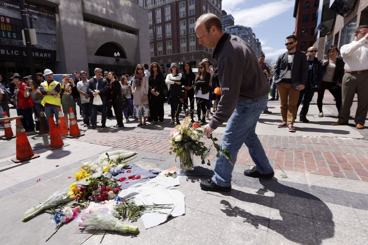 David Robbins of Needham, Mass., places flowers at the site where the first bomb detonated April 15 near the finish line of the Boston Marathon on Boylston Street.