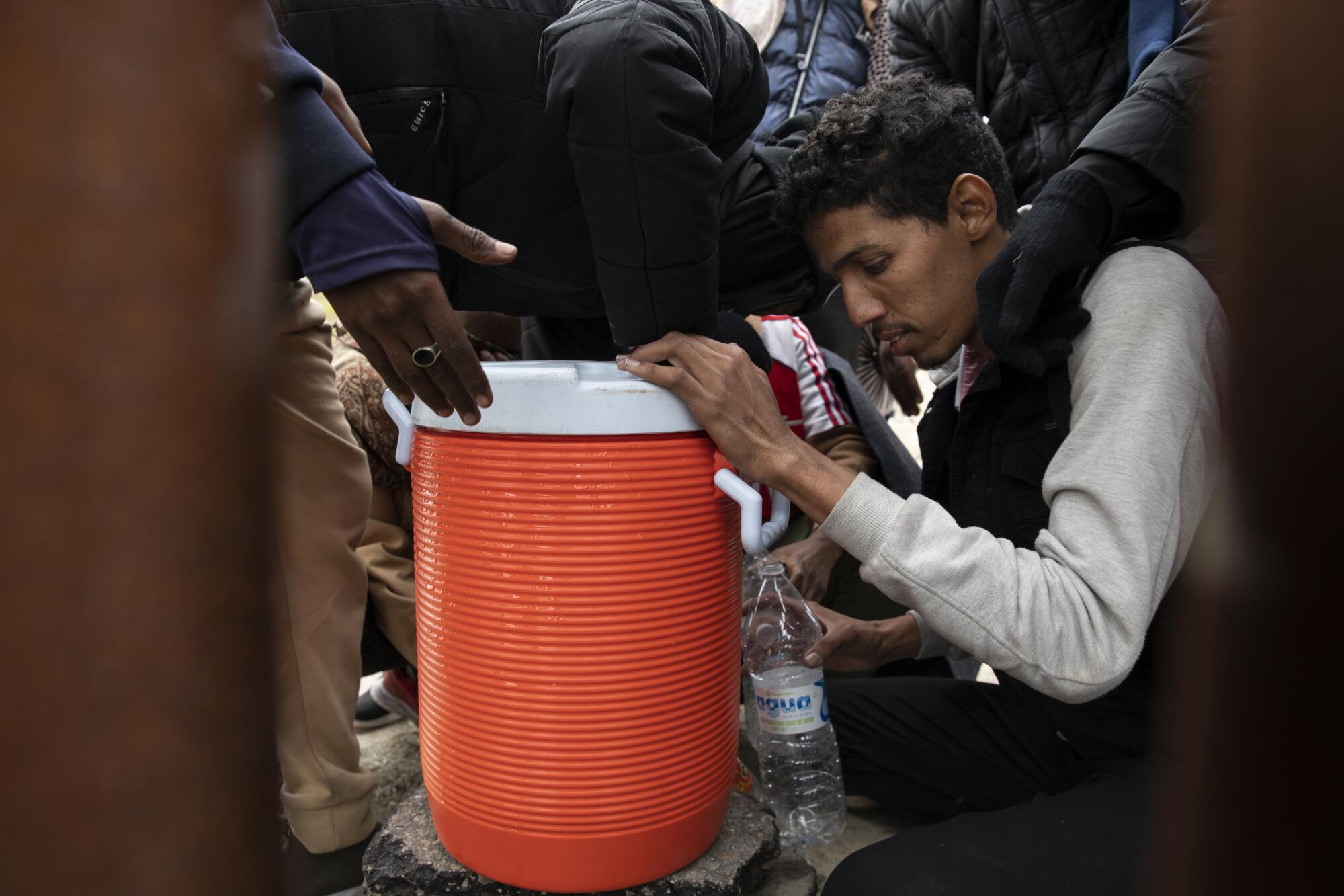 Asylum-seeking migrants gather to get water left by U.S. Border Patrol agents.