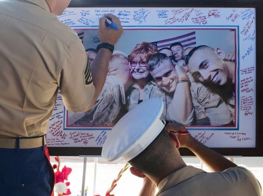 Marines write condolence messages on a photograph of Laura Froehlich at Riverside National Cemetery. Her warm smiles and hugs were welcomed by troops returning from battle and those heading to the war zone.