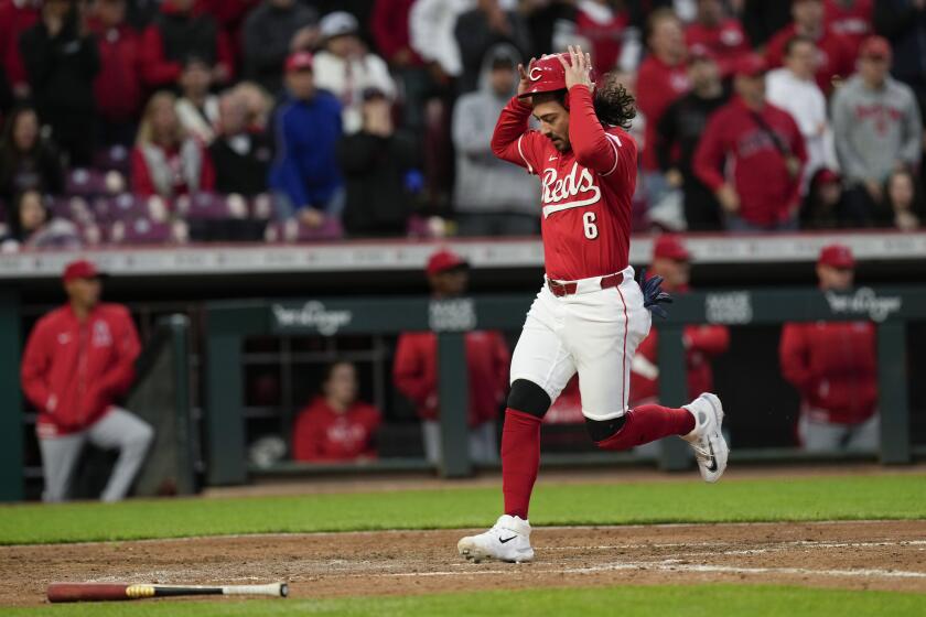 Jonathan India, de los Rojos de Cincinnati, agarra su casco mientras anota con un sencillo de Stuart Fairchild contra los Angelinos de Los Ángeles durante la quinta entrada de un juego de béisbol el sábado 20 de abril de 2024, en Cincinnati. (AP Foto/Carolyn Kaster)