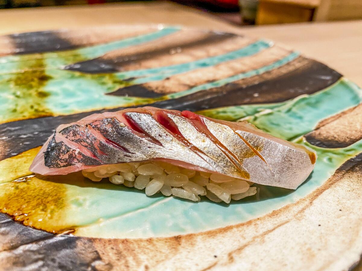 Raw fish atop grains of rice on a colorful plate.