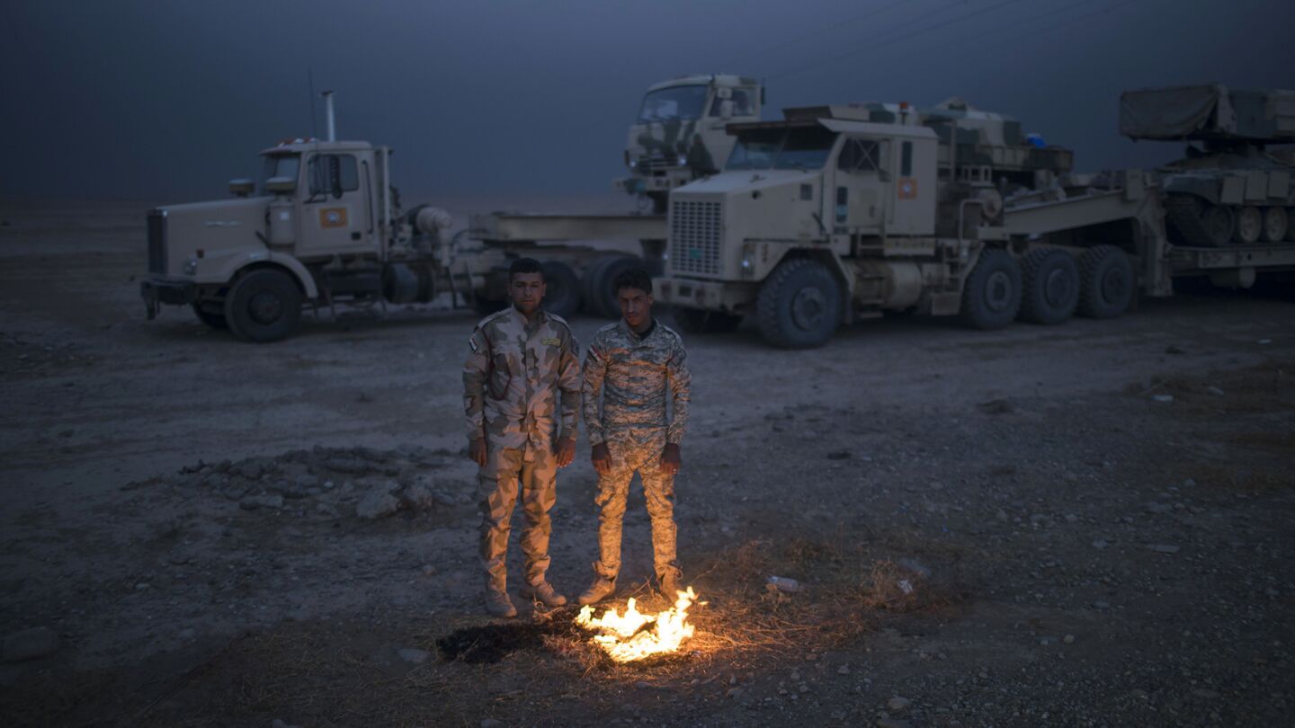 Iraqi army soldiers warm themselves near the Qayyarah air base, south of Mosul, on Tuesday.