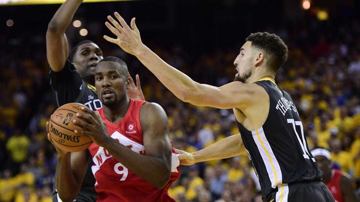 Toronto Raptors center Serge Ibaka (9) holds the ball as Golden State Warriors guard Klay Thompson, right, defends during the second half of Game 4 of the NBA Finals on Friday in Oakland.