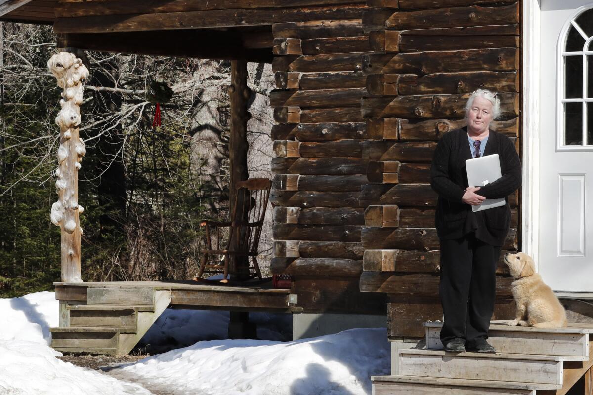 Julie Dolan, presidente de la Comisión de Banda Ancha de su pueblo, posa con su computadora en las escaleras de su casa en Sandwich, Nueva Hampshire, el jueves 26 de marzo de 2020. (AP Foto/Charles Krupa)