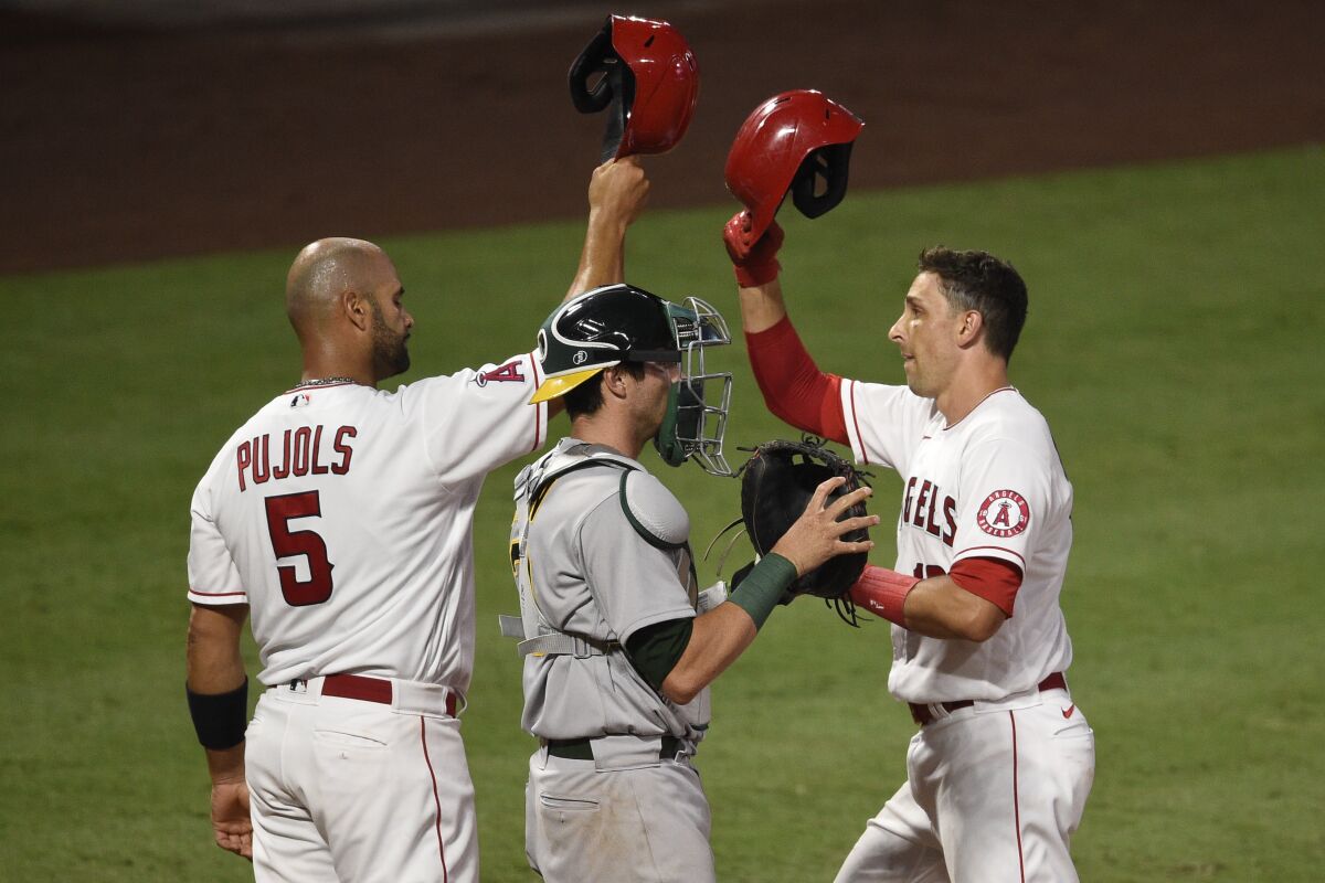 Los Angeles Angels' Jason Castro, right, celebrates with Albert Pujols, left, after hitting a three-run home run during the fourth inning of a baseball game as Oakland Athletics catcher Austin Allen looks on in Anaheim, Calif., Tuesday, Aug. 11, 2020. (AP Photo/Kelvin Kuo)