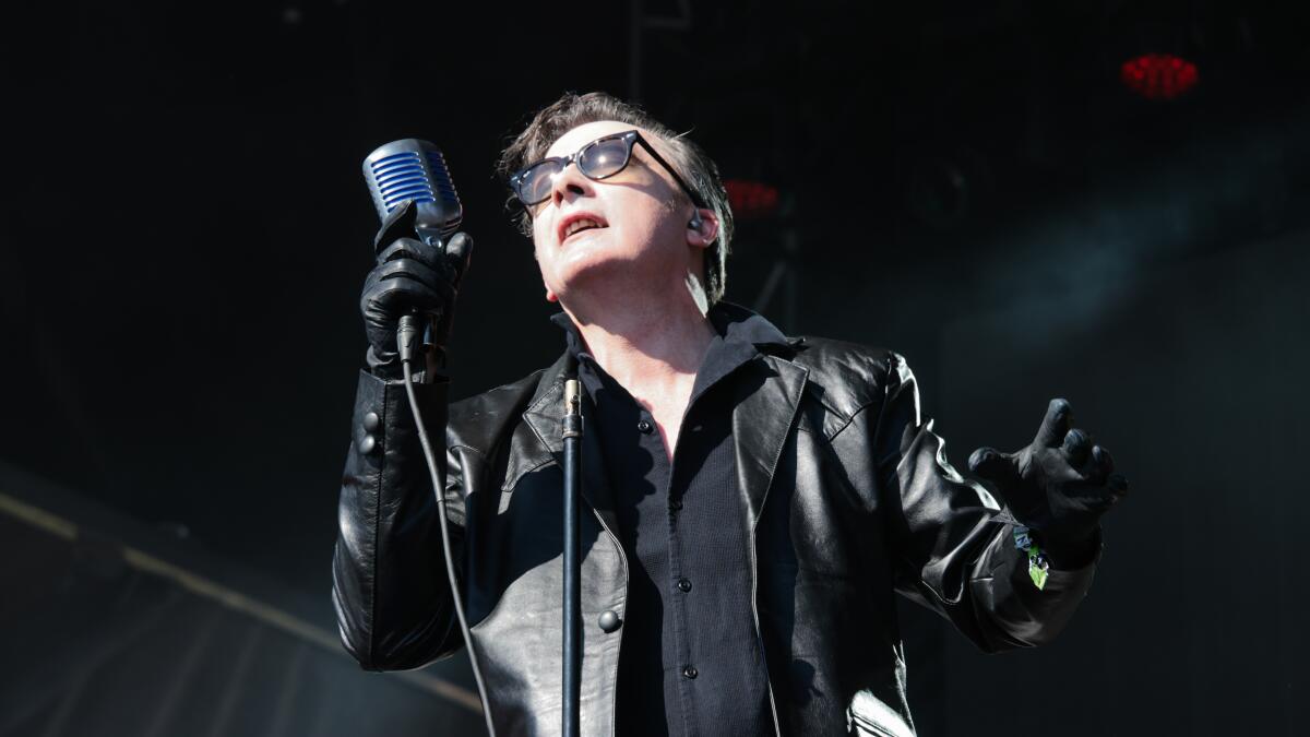 Punk singer in black leather jacket and black glasses holding microphone