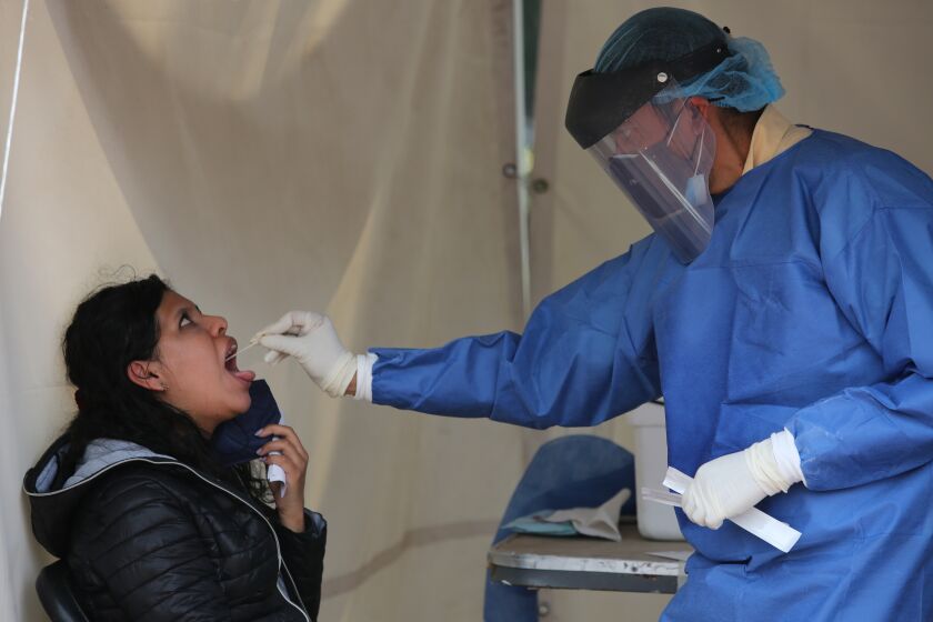 Un trabajador de la salud toma una muestra de la garganta de una mujer para hacer una prueba de detección de COVID-19 en Ciudad de México el sábado 10 de julio de 2021. (AP Foto/Ginnette Riquelme)