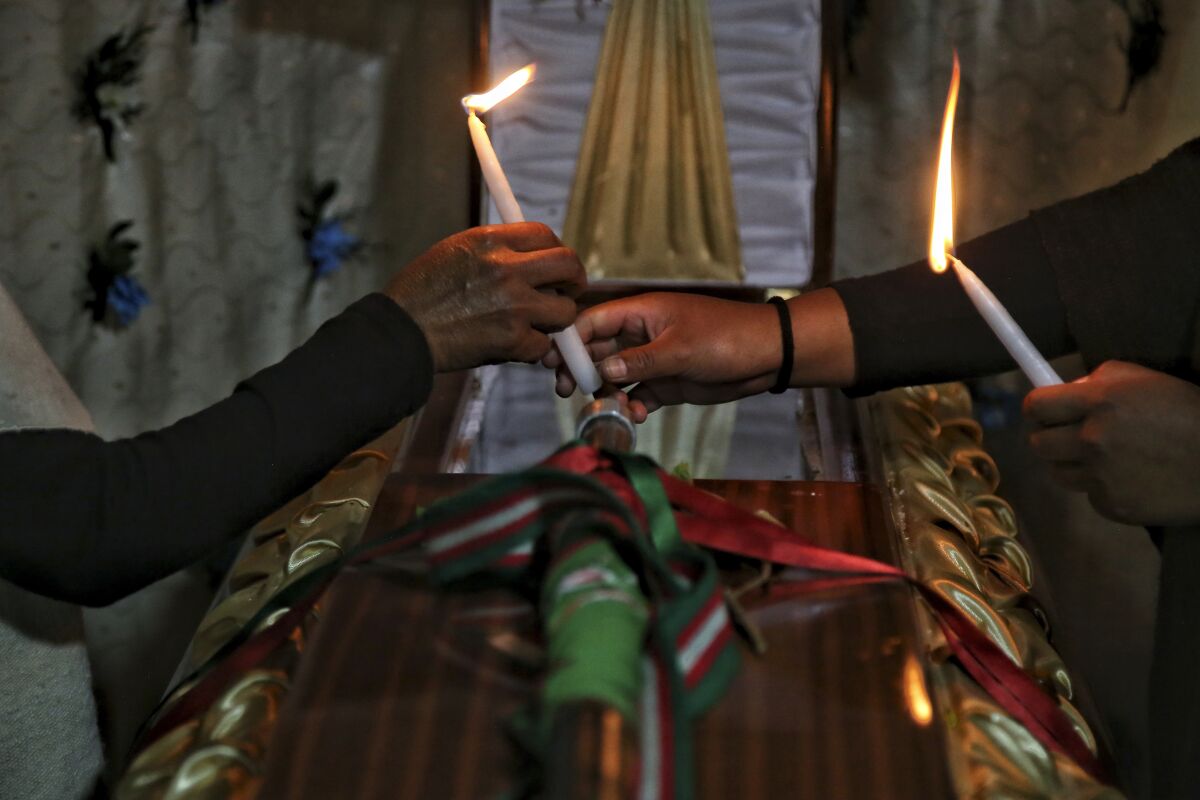 ARCHIVO - Deudos encienden velas sobre el ataúd con los restos del líder indígena Wilson Bomba,