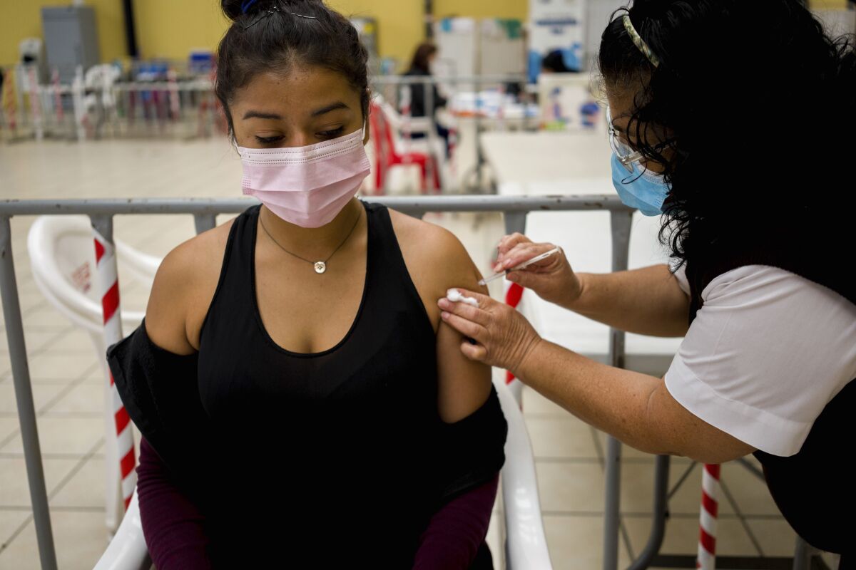A healthcare worker administers an AstraZeneca booster shot for COVID 19 at a vaccination center in Guatemala City, Tuesday, March 1, 2022. (AP Photo/Moises Castillo)