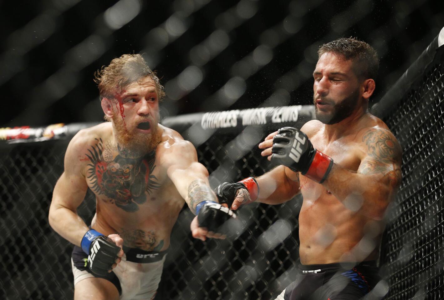 Conor McGregor sends Chand Mendes reeling with a left during their interim featherweight championship fight on Saturday night at UFC 189 in Las Vegas.