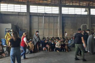 Survivors of a shipwreck sit in a warehouse, at the port in Kalamata town, about 240 kilometers (150miles) southwest of Athens on Wednesday, June 14, 2023. Authorities say at least 30 people have died after a fishing boat carrying dozens of migrants capsized and sank off the southern coast of Greece. A large search and rescue operation is underway. (www.argolikeseidhseis.gr via AP)