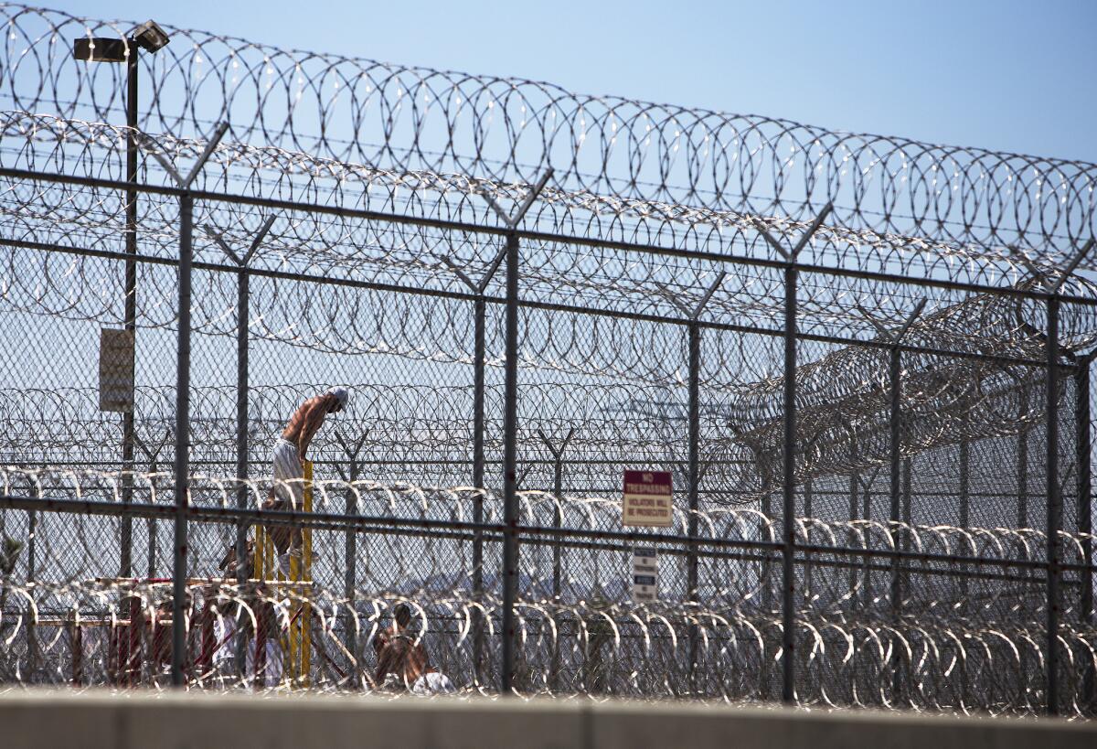 Detainees work out in the yard behind double fencing and barbed wire at the Adelanto Detention Center in 2014.