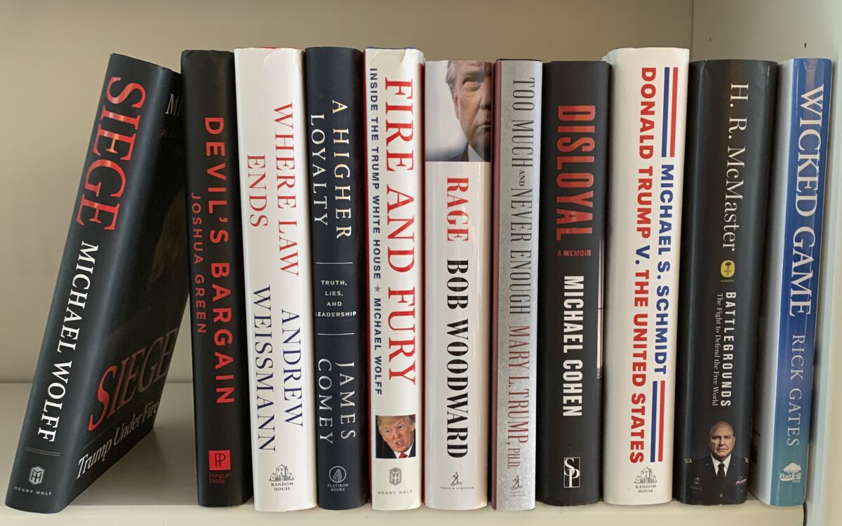 Eleven recently published books about President Trump stand on a shelf. 