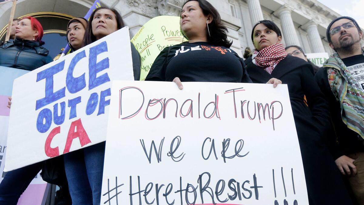 Protesters hold signs as they listen to speakers at a rally outside of City Hall in San Francisco on Jan. 25, 2017.