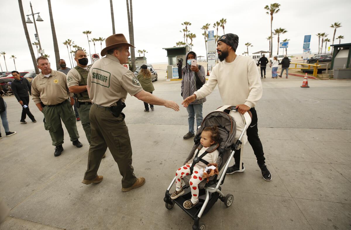 Sheriff Alex Villanueva shakes the hand of a man walking his baby in a stroller.