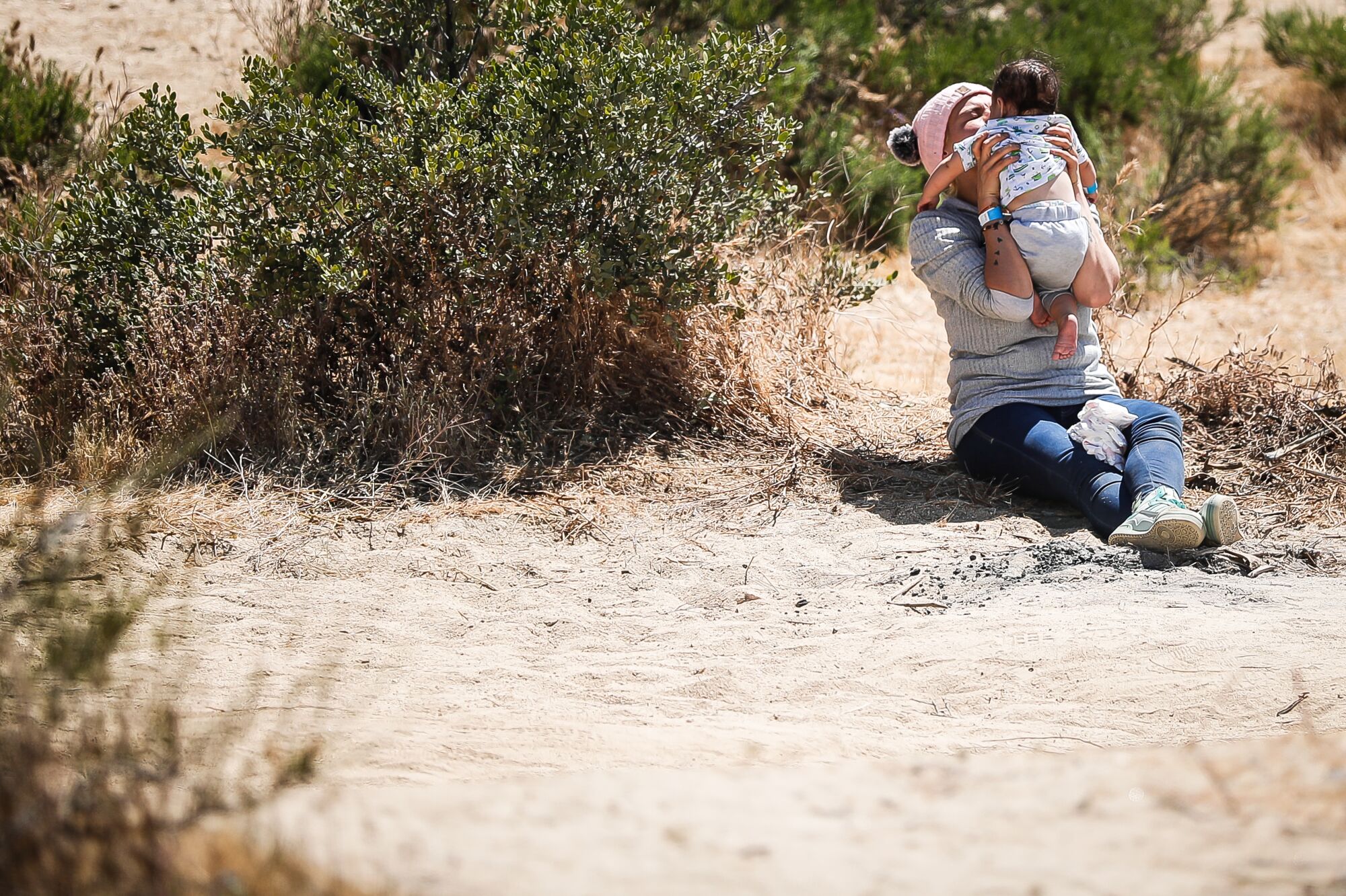A migrant woman coddles an infant on Friday, May 12, 2023, in Jacumba Hot Springs, CA.