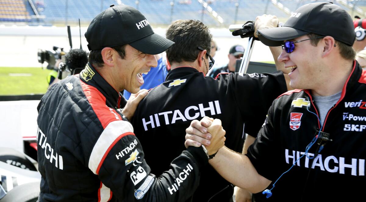 Helio Castroneves, left, celebrates with a crew member Saturday after winning the pole position for the IndyCar Series ace at Iowa Speedway.
