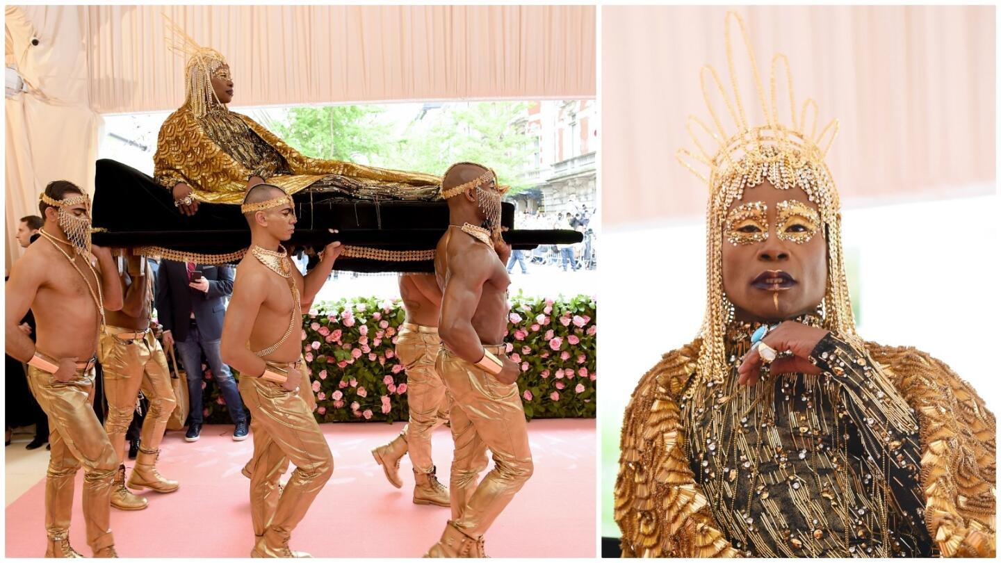 "Pose" star Billy Porter is carried into the 2019 Met Gala by six shirtless men. For the occasion, Porter is in a custom look by the Blonds that includes a bejeweled golden catsuit with 10-foot wings, a 24-karat gold headpiece and golden eye makeup.