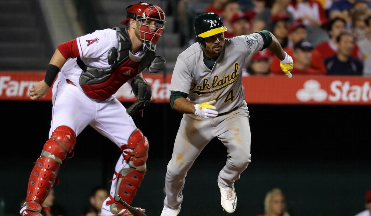 Oakland Athletics' Coco Crisp, right, singles as Angels catcher Jett Bandy looks on during the sixth inning on Saturday at Angel Stadium.