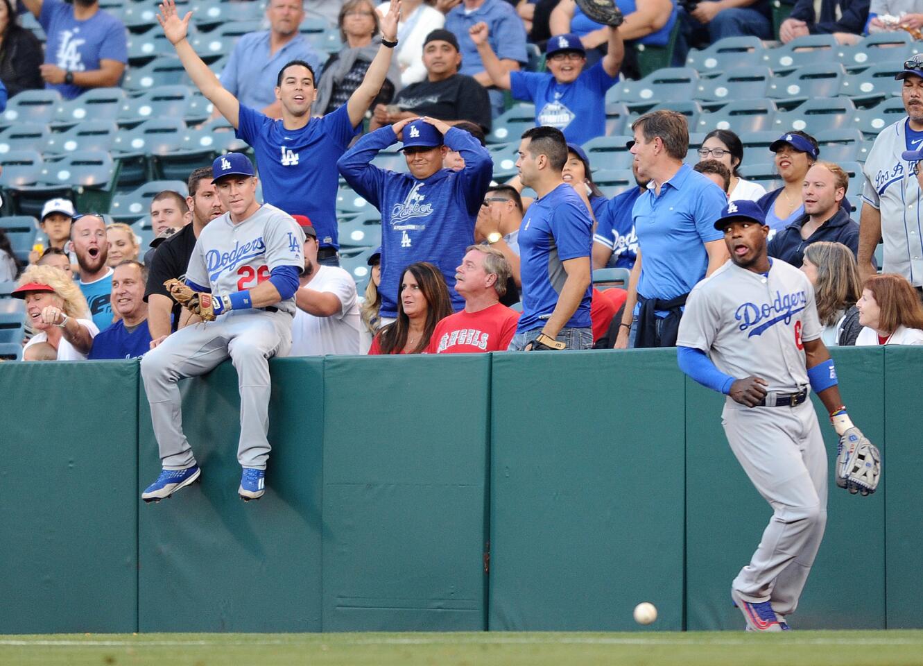 Dodgers second baseman Chase Utley takes a seat on the wall after he and right fielder Yasiel Puig couldn't track down a foul ball hit by the Angels' Yunel Escobar in the first inning.