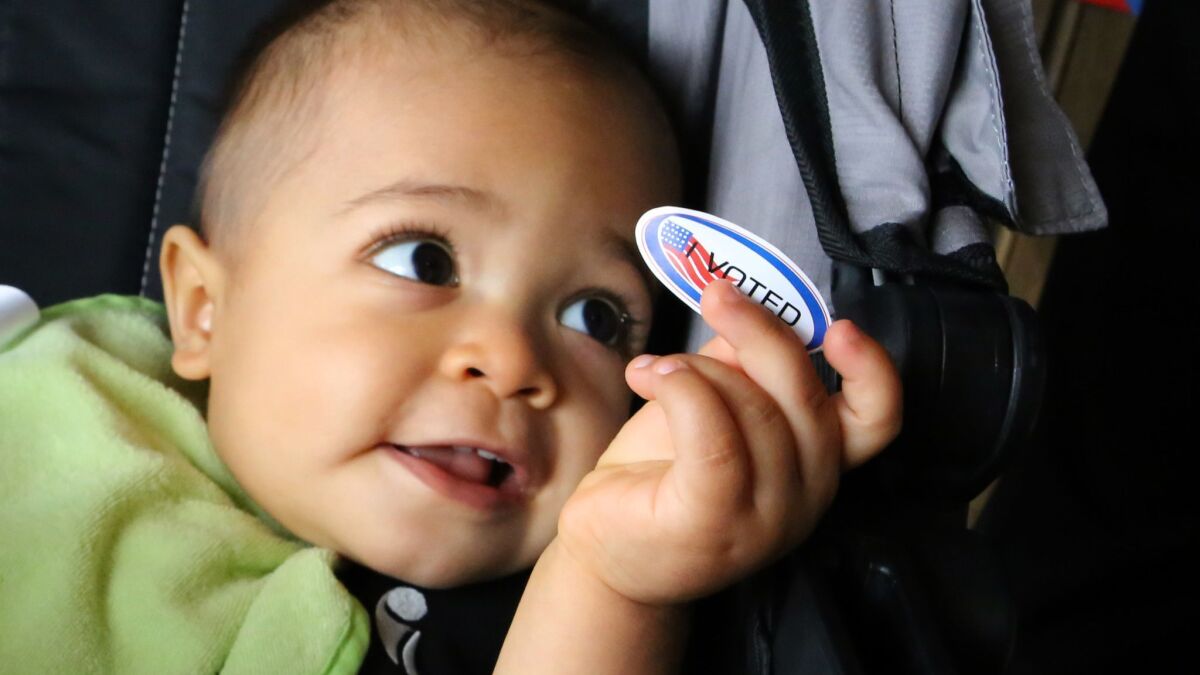 Sebastian Villegas, 14 months old, holds an "I Voted" sticker from his dad Epi Villegas. He'll have to wait until the 2032 election for his turn.