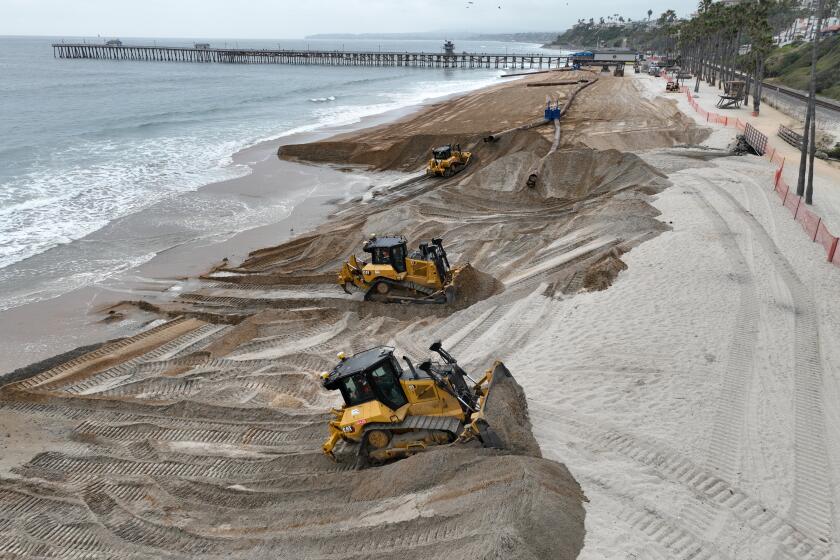 San Clemente, CA - May 02:Workers replenish the beach with new sand south of the pier during the first part of a sand replenishment project in San Clemente Thursday, May 2, 2024. New sand sits south of the pier and the old, rocky sand is on the north side during the first part of a sand replenishment project (Allen J. Schaben / Los Angeles Times)