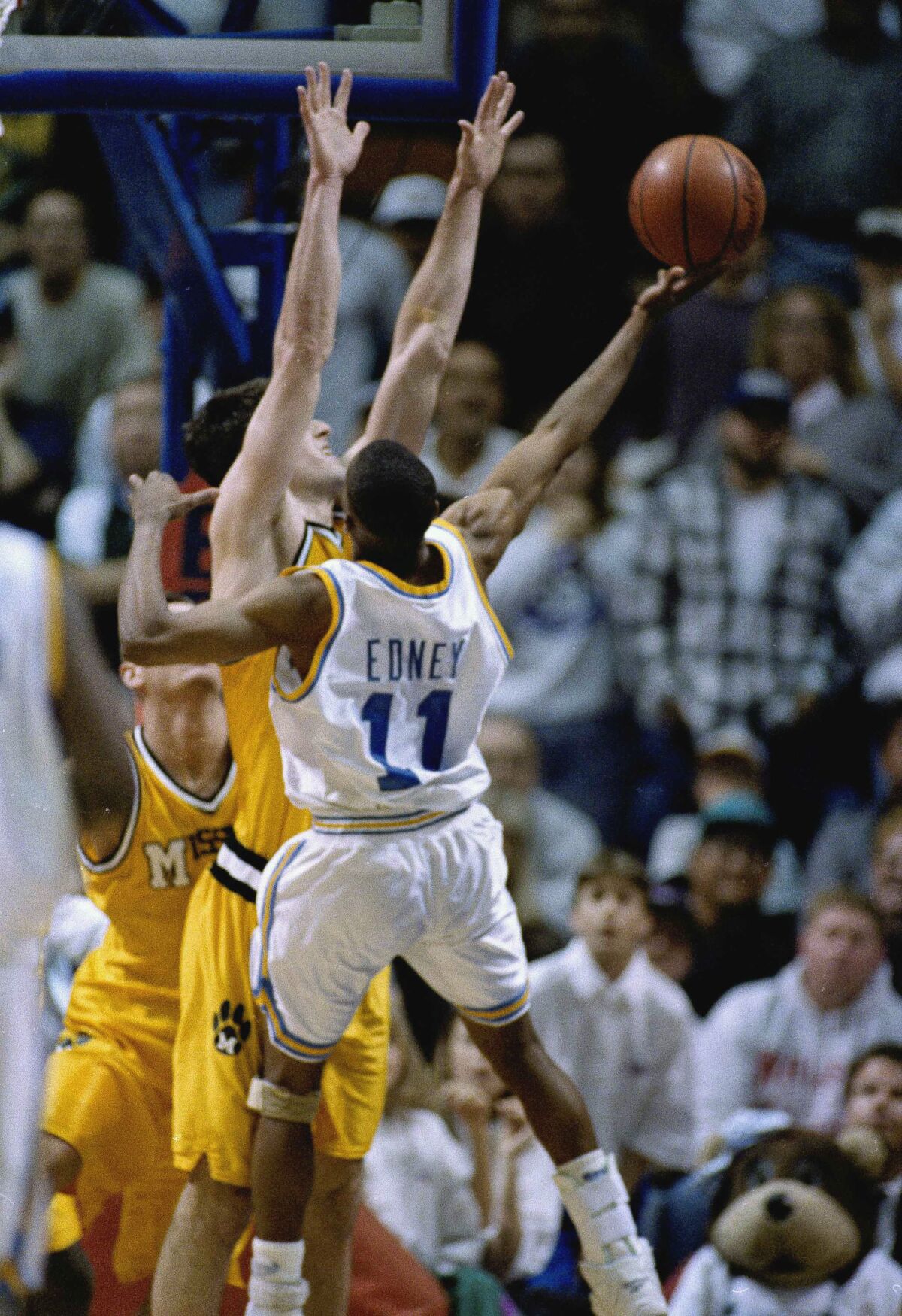 Tyus Edney leaps as he makes a shot on court.