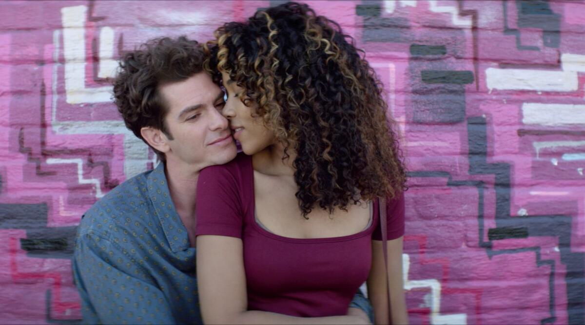 A man hugs a woman seated on his lap.