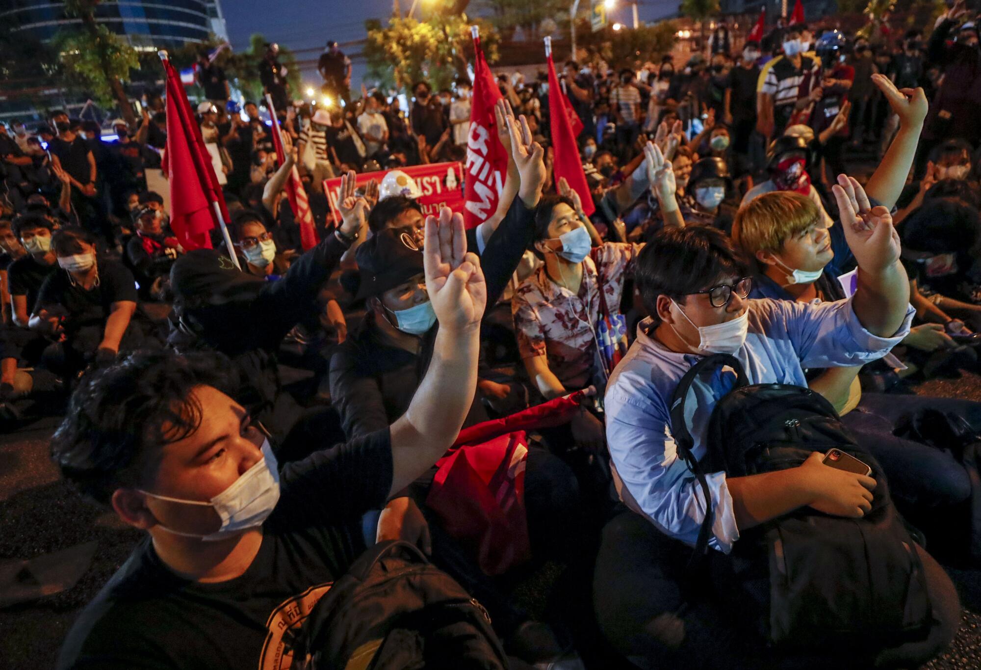 A crowd with red flags flashes the three-finger salute 